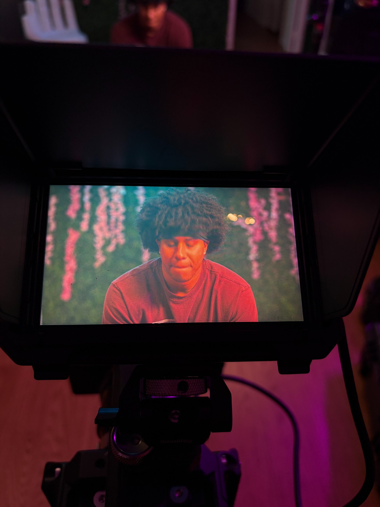 Behind the scenes: a camera monitor showing an actor under colorful lighting